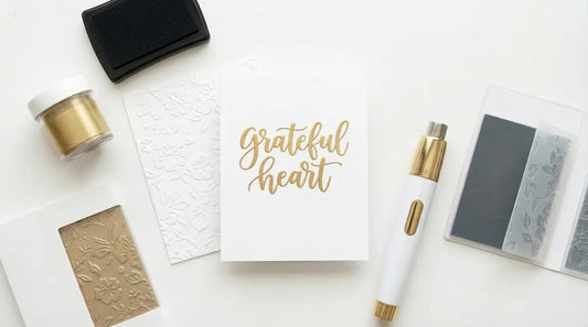 Embossing tools for heat and dry embossing beside embossed card panels on a craft table.