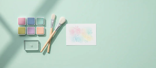 Pastel ink pads, blending brushes, and a small ink-blended floral cardstock panel arranged on a soft background