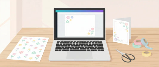 Cozy pastel craft desk with a laptop design canvas, printed floral clipart sheet, and finished greeting card with scissors and washi tape.